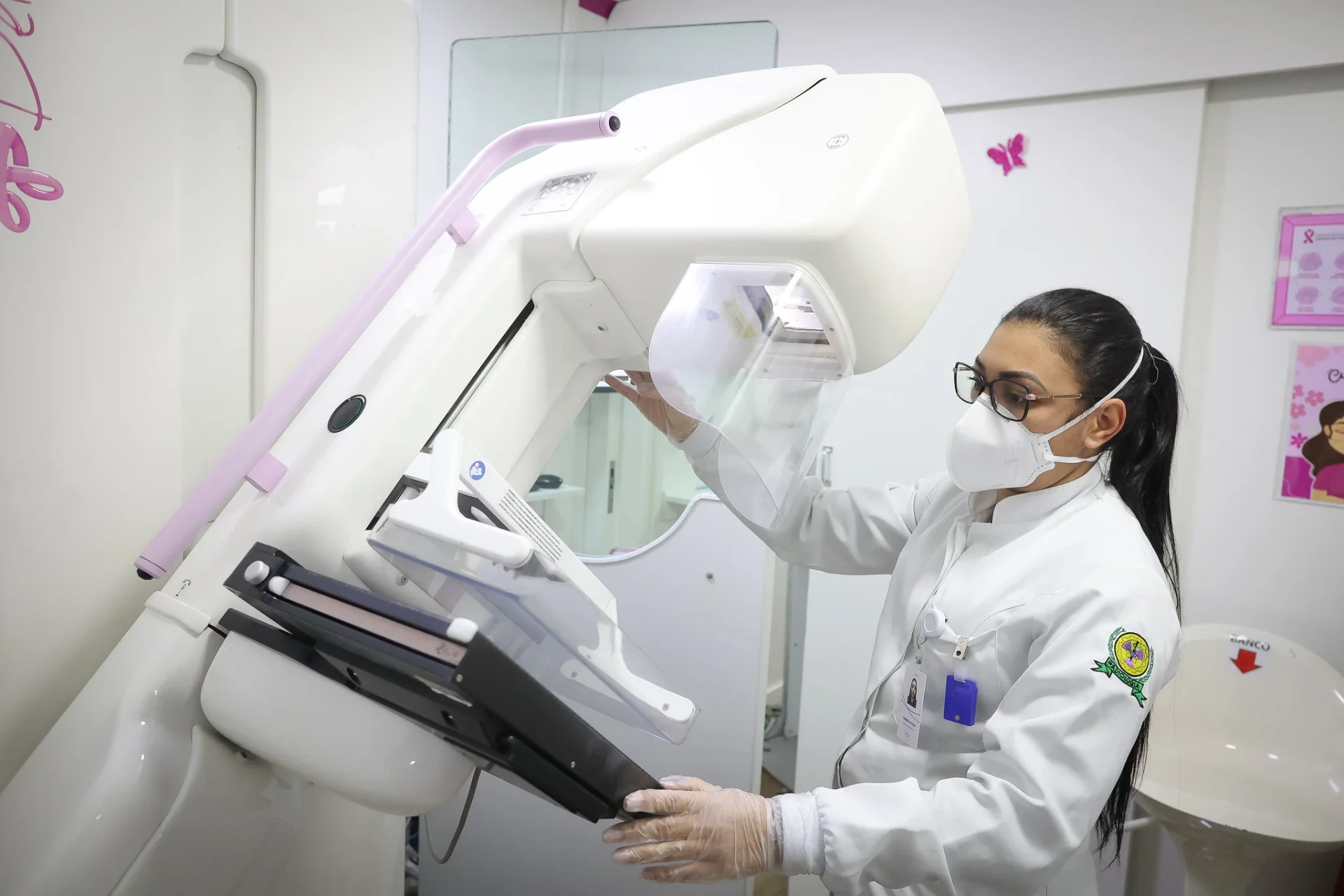 Profissional de saúde ajusta aparelho de mamografia
