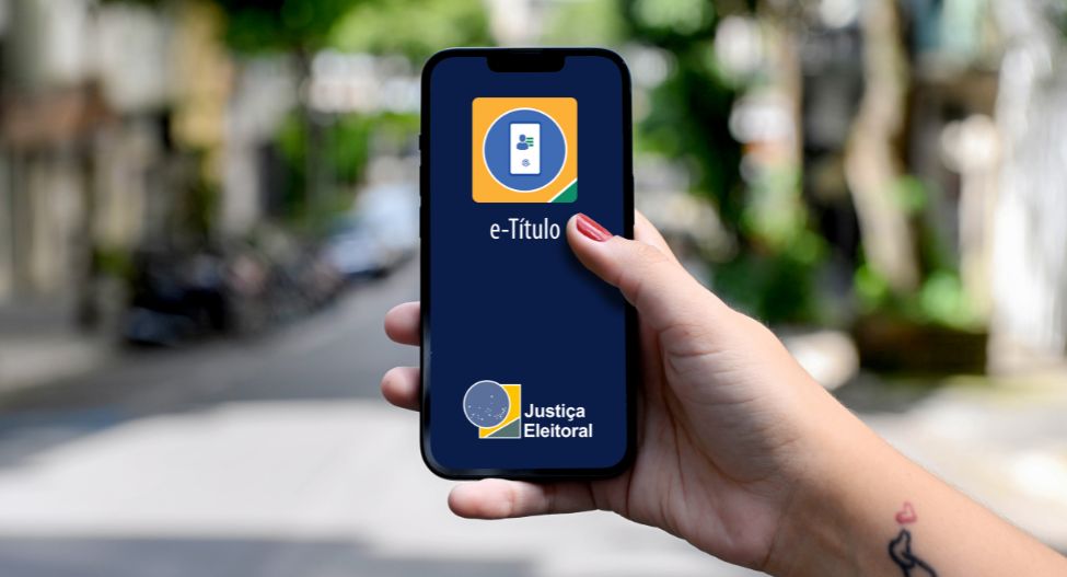 Mão segurando celular com o aplicativo e-Título da Justiça Eleitoral na tela
