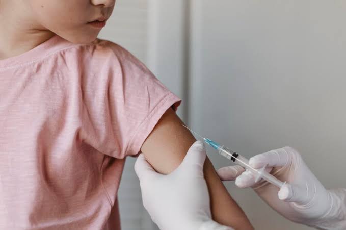 Criança recebe uma dose de vacina no braço